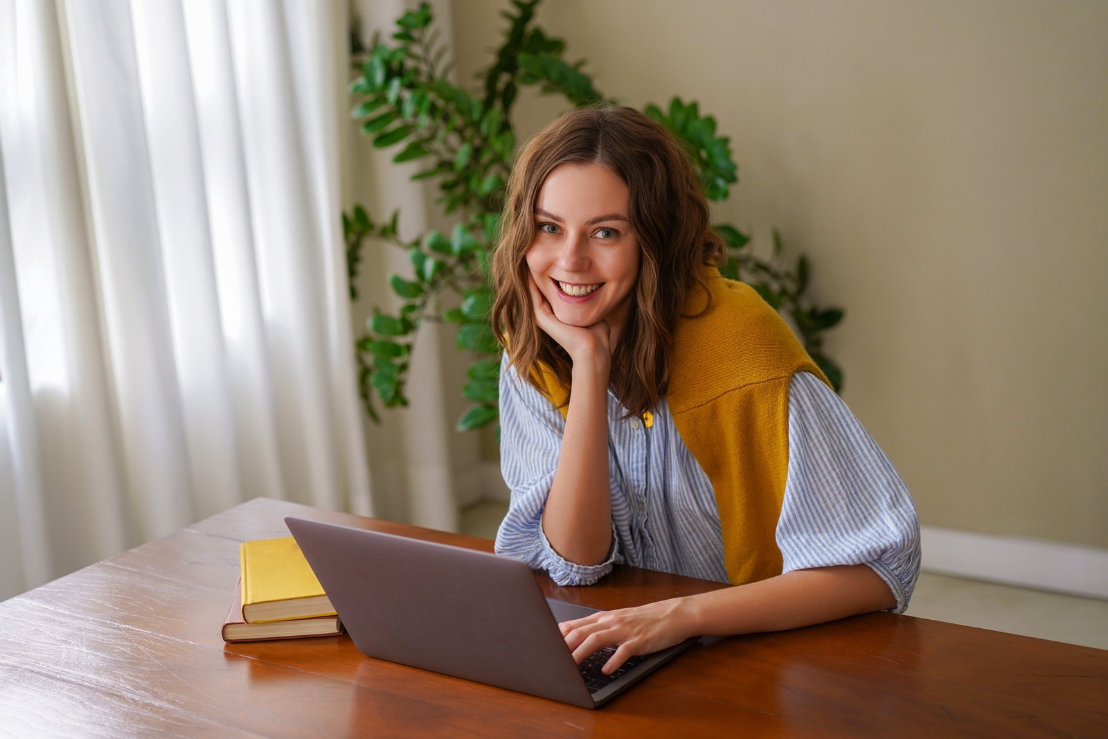 Uśmiechnięta młoda kobieta przy laptopie w domu