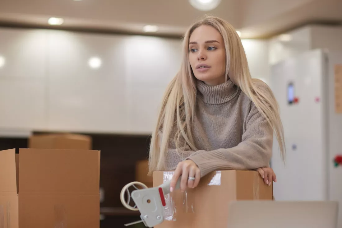 Mloda kobieta pakuje rzeczy do kartonu w biurze