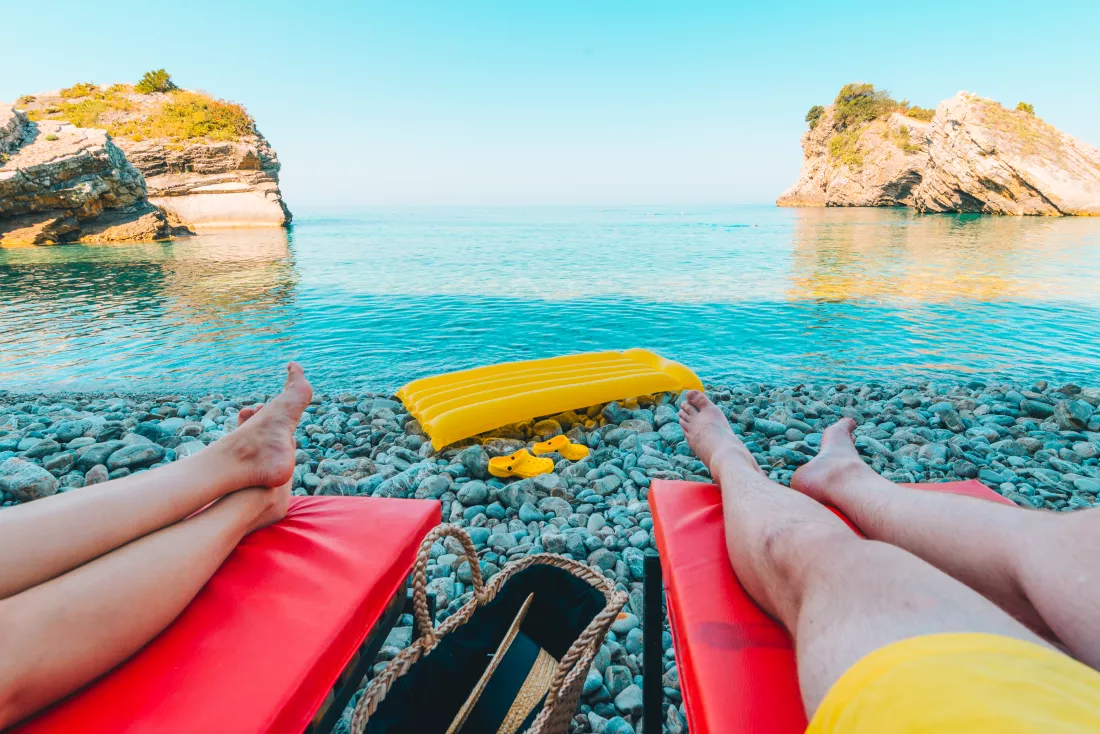 couple-laying-sun-loungers-with-beautiful-view-sea-with-rocks