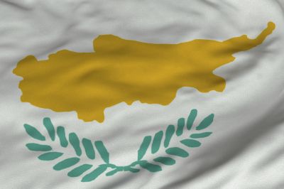 Flaga Cypru - w centrum umieszczone są: figura przypominająca wyspę Cypr oraz 2 zielone gałązki oliwne